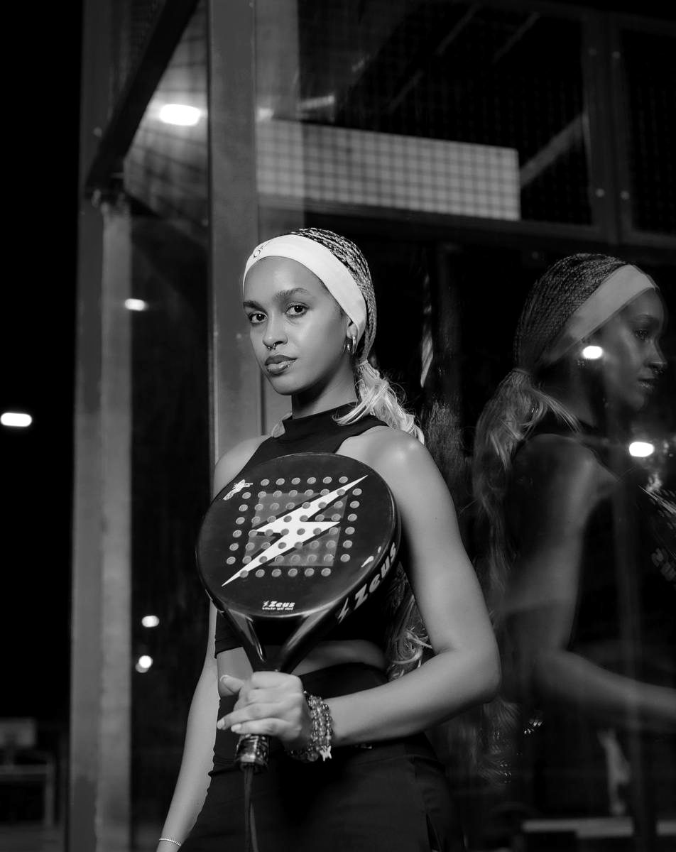 A padel player holding her racket on an outdoor court at night