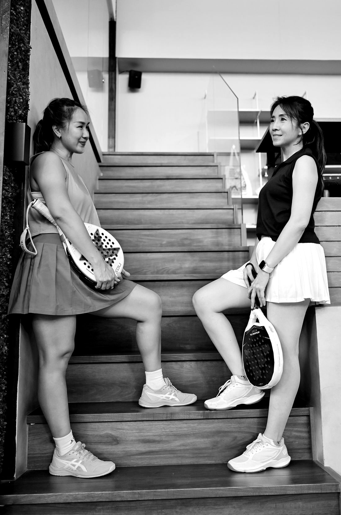 Two women with padel rackets smiling at each other